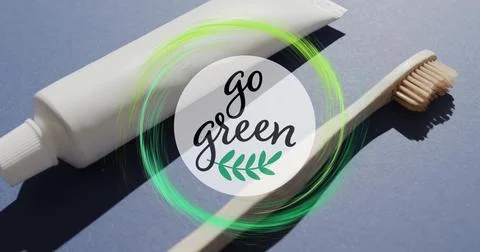 Image of go green text and green ring over toothpaste tube and wooden toothbrush Stock Photos