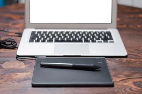 Image of a graphics tablet, stylus and laptop on a wooden table. Designer w.. Stock Photos