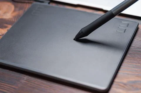 Image of a graphics tablet, stylus and laptop on a wooden table. Designer w.. Stock Photos