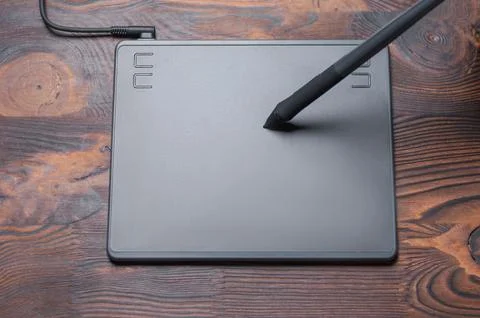 Image of a graphics tablet, stylus and laptop on a wooden table. Designer w.. Stock Photos