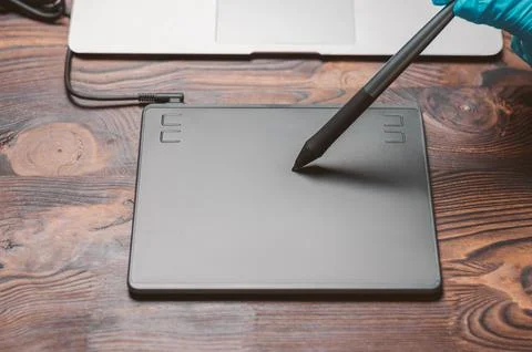 Image of a graphics tablet, stylus and laptop on a wooden table. Designer w.. Stock Photos