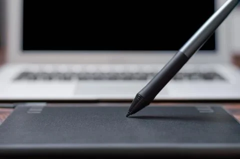 Image of a graphics tablet, stylus and laptop on a wooden table. Designer w.. Stock Photos
