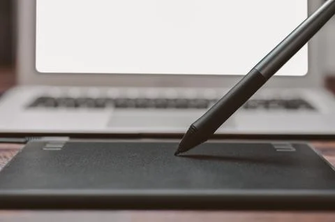 Image of a graphics tablet, stylus and laptop on a wooden table. Designer w.. Stock Photos