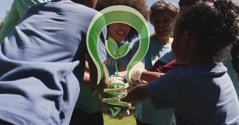 Image of green light bulb logo over happy african american group stacking hands Stock Photos