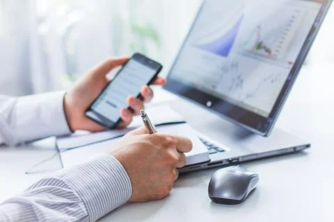 An image of the hands of a man sitting at a table and writing in a Notepad wi Stock Photos