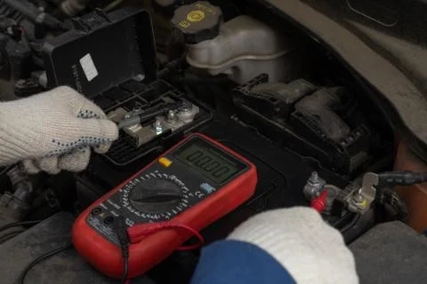 Image of hands with a multimeter voltmeter to check the voltage level in a ca Stock Photos