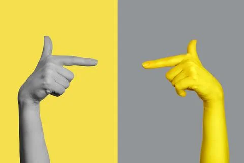 An image of hands pointing at each other. The hand is gray and yellow. Stock Photos
