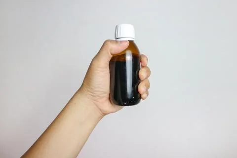 Image of hands with table spoon and bottle of medication. Pouring cough syr.. Stock Photos