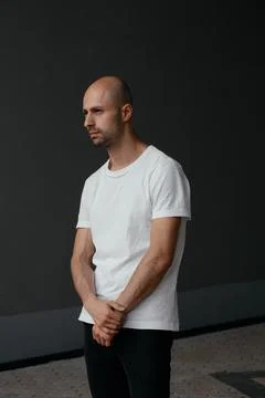 Image of a handsome bald man in a white T-shirt on a gray background Stock Photos