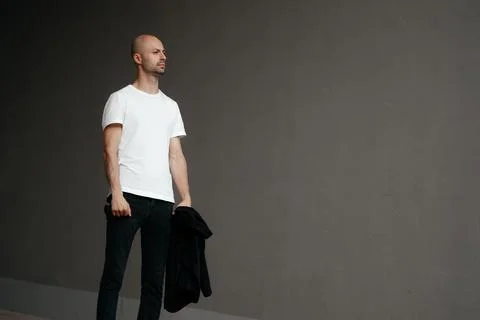 Image of a handsome bald man in a white T-shirt on a gray background Foto stock