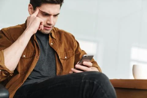 Image of handsome brooding man using mobile phone while working Stock Photos
