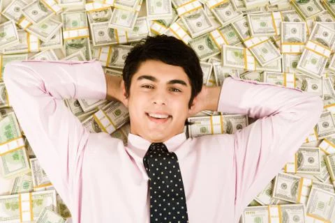 Image of happy businessman lying on heap of dollars and smiling Stock Photos