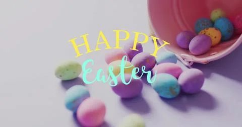 Image of happy easter text over colourful easter eggs and pink bucket on purple Stock Photos