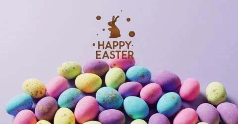 Image of happy easter text over colourful easter eggs on purple background Stock Photos