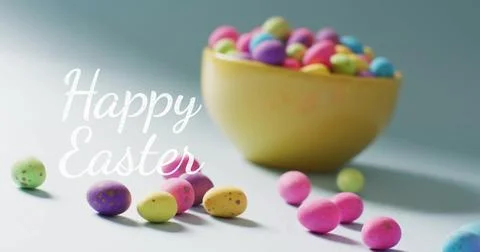 Image of happy easter text over colourful easter eggs in bowl on blue background Stock Photos