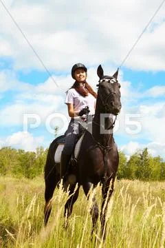 Image of happy female jockey sitting on purebred horse outdoors Stock Photos