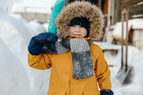 Image of a happy five-six-year-old kid in an orange jacket looks into the camera Stock Photos