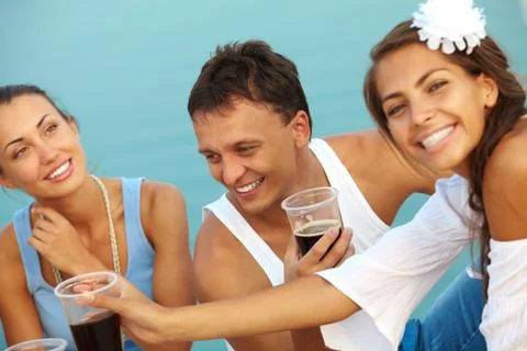 Image of happy guy with drink surrounded by girls at beach party Foto stock