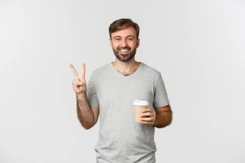 Image of happy guy drinking takeaway coffee, showing peace sign and smiling Foto stock