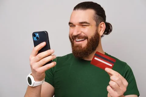 Image of happy handsome man with beard buying something online with credit card 스톡 사진