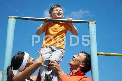 Image of happy parents helping their son to do physical exercise Stock Photos