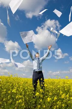 Image of happy winner throwing papers in yellow meadow Stock Photos