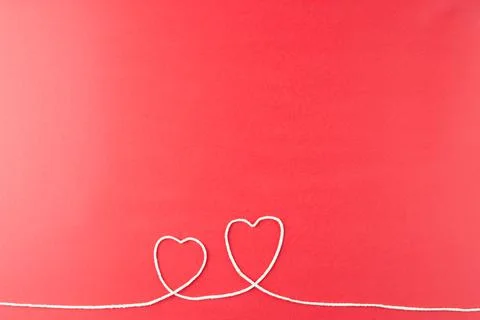 Image of hearts made of white string on red surface Stockfoto's