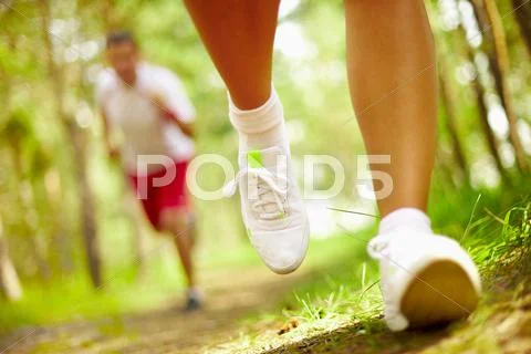 Image of human feet in sportshoes running down grass Stock Photos