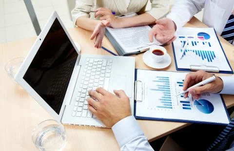 Image of human hands during work with laptop and business documents at meeting Stock Photos