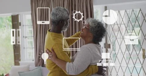 Image of icons and data processing over biracial senior couple dancing at home Foto stock
