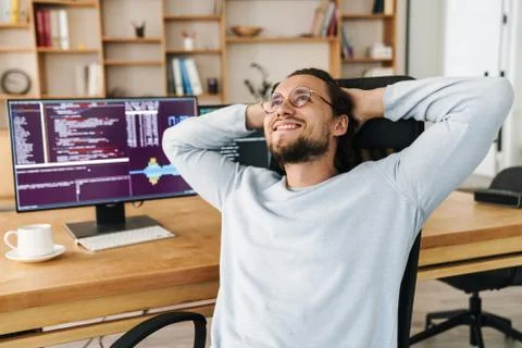 Image of joyful programmer man smiling and resting while working Stock Photos
