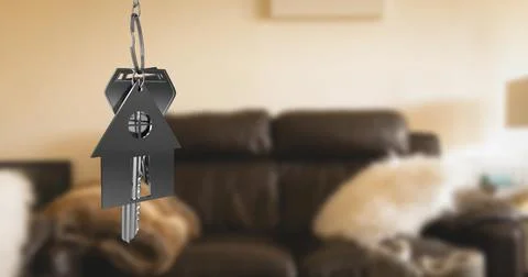 Image of key with keychain in shape of house over living room interior Ilustração Stock
