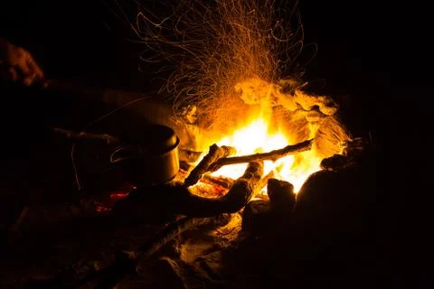 Image of a large campfire, around which people basking in the mountains at night Stock Photos