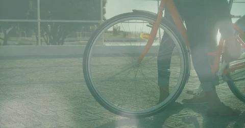 Image of light spots over biracial couple with bicycle at seaside Fotos Stock
