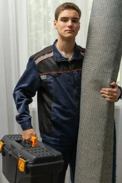 Image of a loader or porter holding a carpet and a tool box. Moving and Reloc Stock Photos
