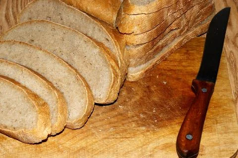 Image of a loaf of bread cut into slices on a kitchen board Stock Photos