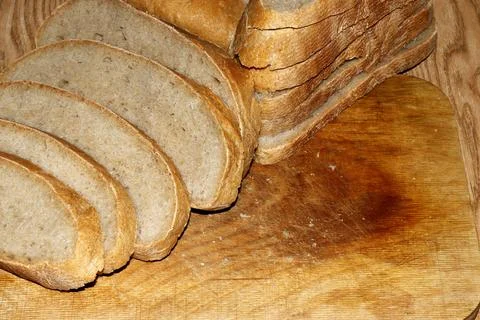 Image of a loaf of bread cut into slices on a kitchen board. Stock Photos