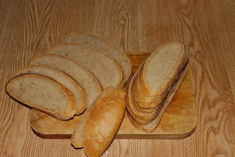 Image of a loaf of bread cut into slices on a kitchen board. Stock Photos