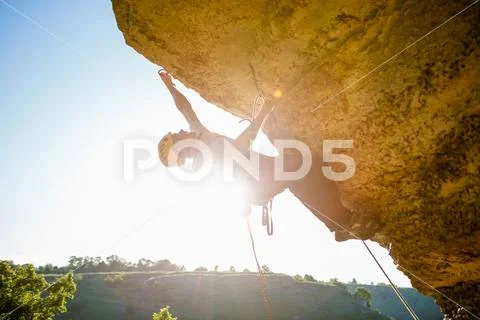 Image of man climber in helmet clambering up cliff. Stock Photos