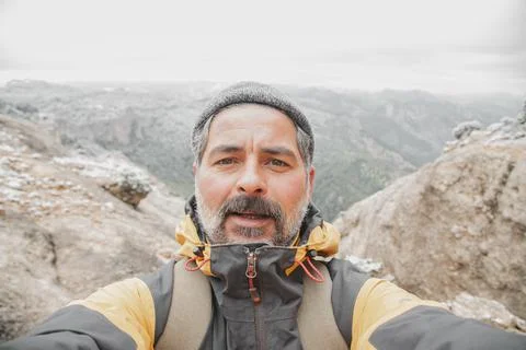 Image of a man doing selfie on top of the mountain looking at camera. Stock Photos