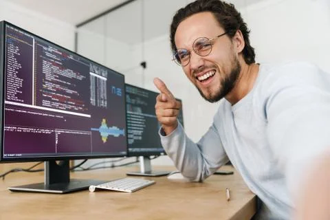 Image of man pointing finger at camera while working with computers Stock-Fotos