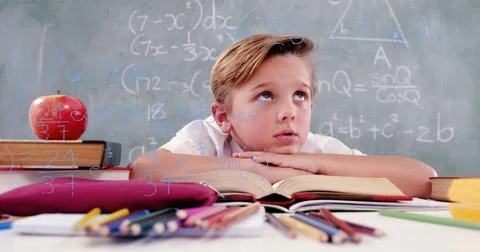 Image of math formulas over thoughtful caucasian boy learning at school Foto stock