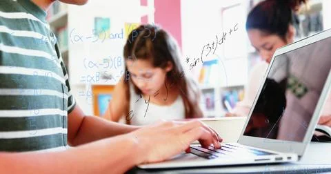 Image of mathematical equations floating over schoolchild using laptop computer Stock Photos