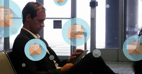 Image of message icons floating over caucasian businessman using digital tablet Stock Photos