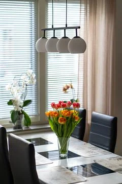 Image of modern kitchen with white table and colourful tulips in the glass vase Stock Photos