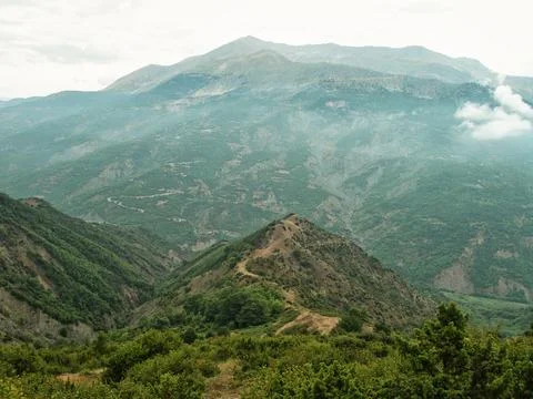 An image of mountains and fields with clouds coming from them Stock Photos