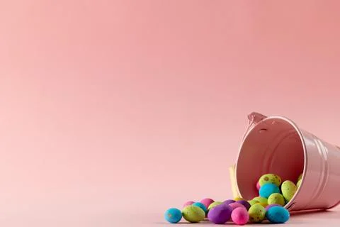 Image of multi coloured easter eggs, pink bucket with copy space on pink Foto stock