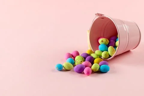 Image of multi coloured easter eggs and pink bucket with copy space on pink Foto stock
