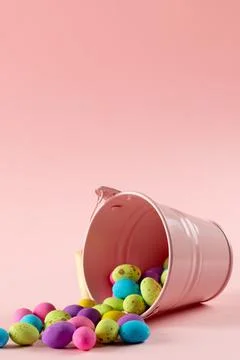 Image of multi coloured easter eggs and pink bucket with copy space on pink Foto stock