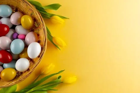 Image of multi coloured easter eggs in basket with yellow tulips and copy space Stock Photos